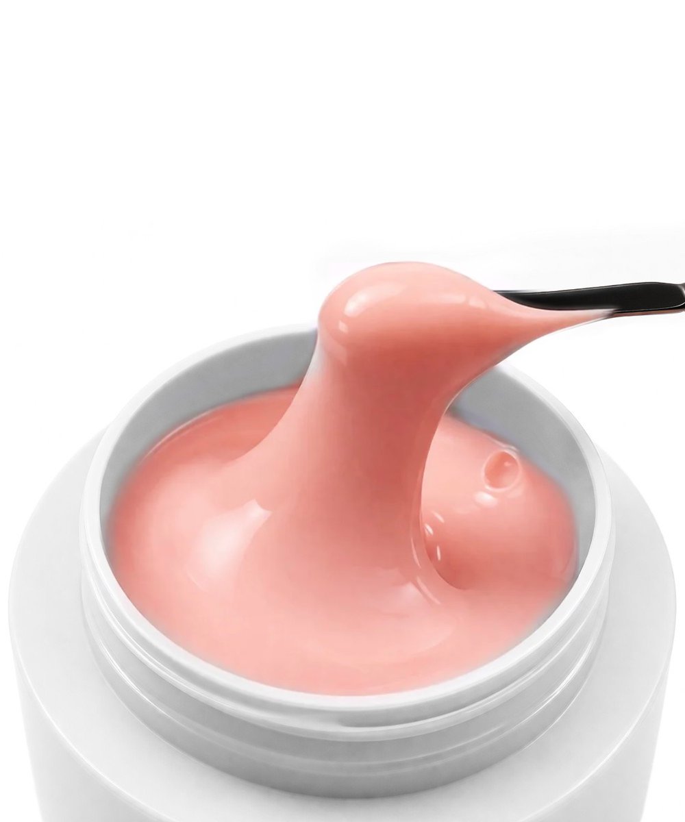 Pink cosmetic cream lifted from an open white jar by a black spatula