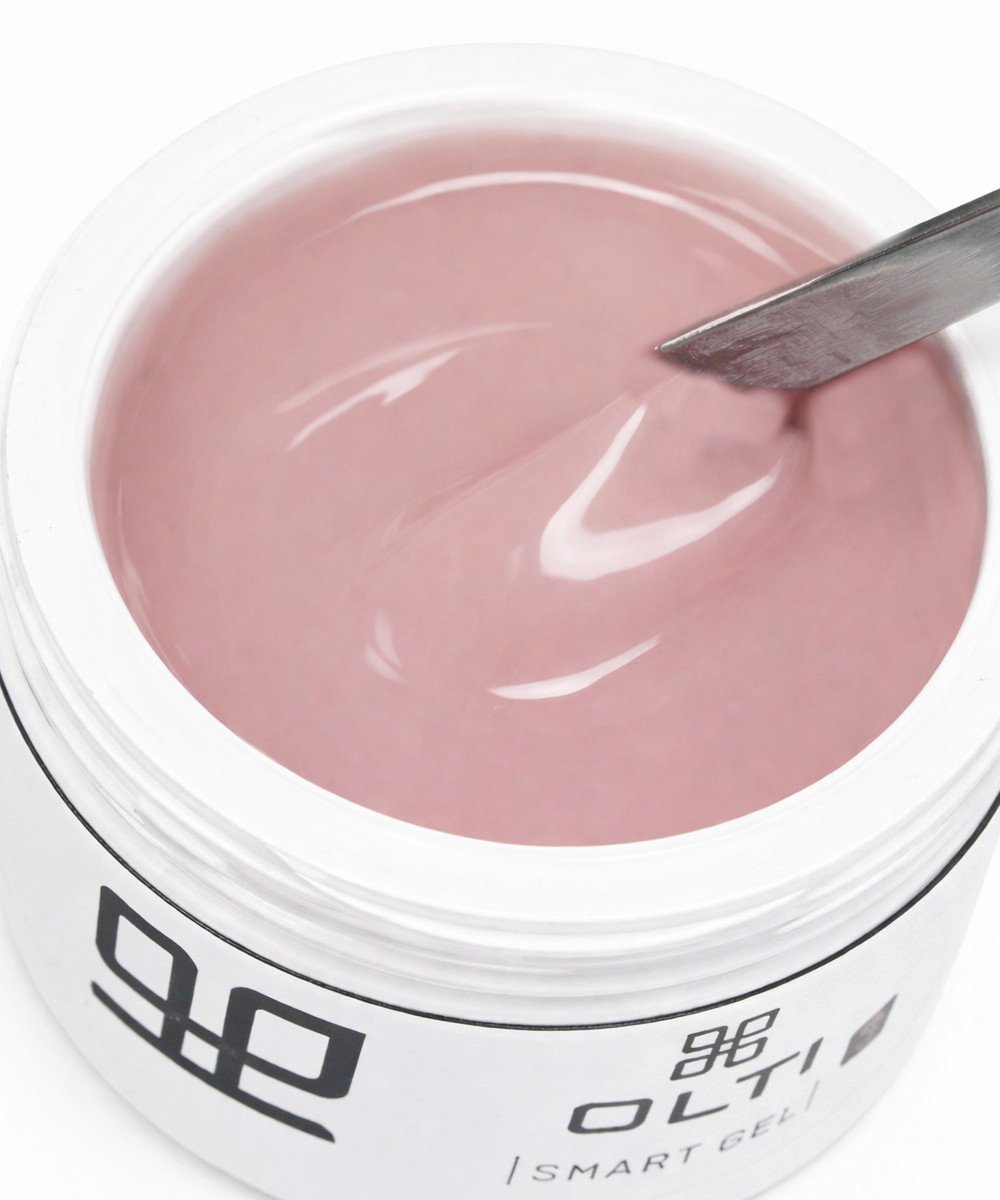 Pink gel nail polish in a white jar with a metal spatula scooping the viscous liquid
