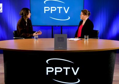 Two women sit at a round studio table with a large PPTV logo on a blue backdrop and a YouTube plaque on the table centerpiece, appearing to record or interview.