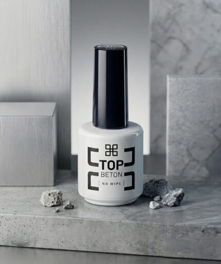 White bottle labeled 'Top Beton No Wipe' with a tall black cap sits on a gray stone surface, surrounded by small rocks.